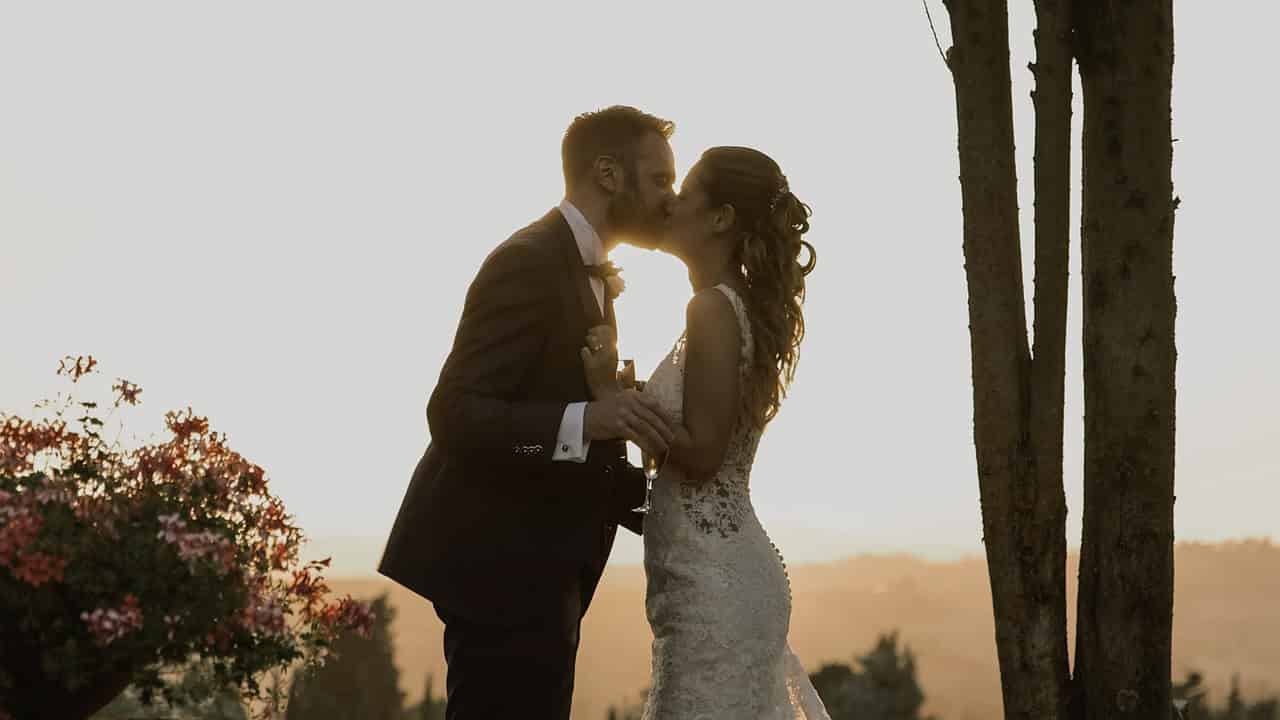 Un tenero bacio tra John e Marianna sotto il sole dorato della Toscana al tramonto, alla Antica Fattoria di Paterno.